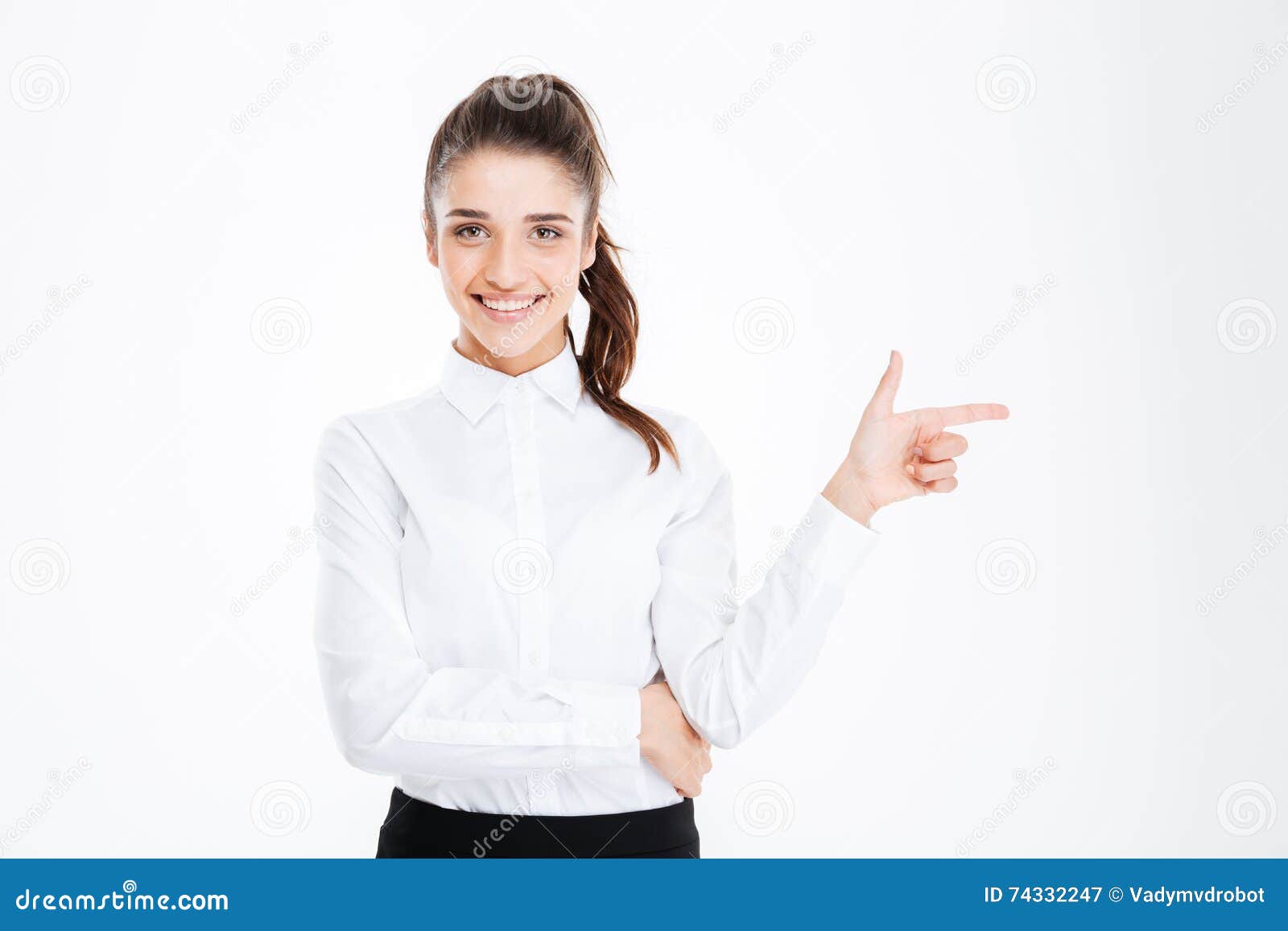 Retrato de una empresaria joven feliz que señala el finger lejos sobre el fondo blanco y que mira la cámara