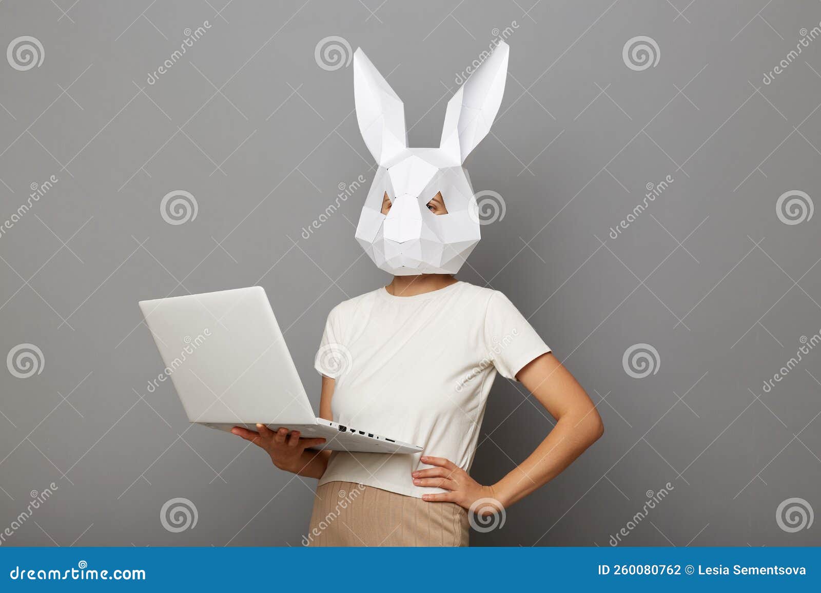 Retrato De Una Mujer Anónima Segura De Sí Misma Con Máscara De Conejo Y Camisa Blanca Aislada Sobre Fondo Gris Trabajando En Una L Foto de archivo  Foto