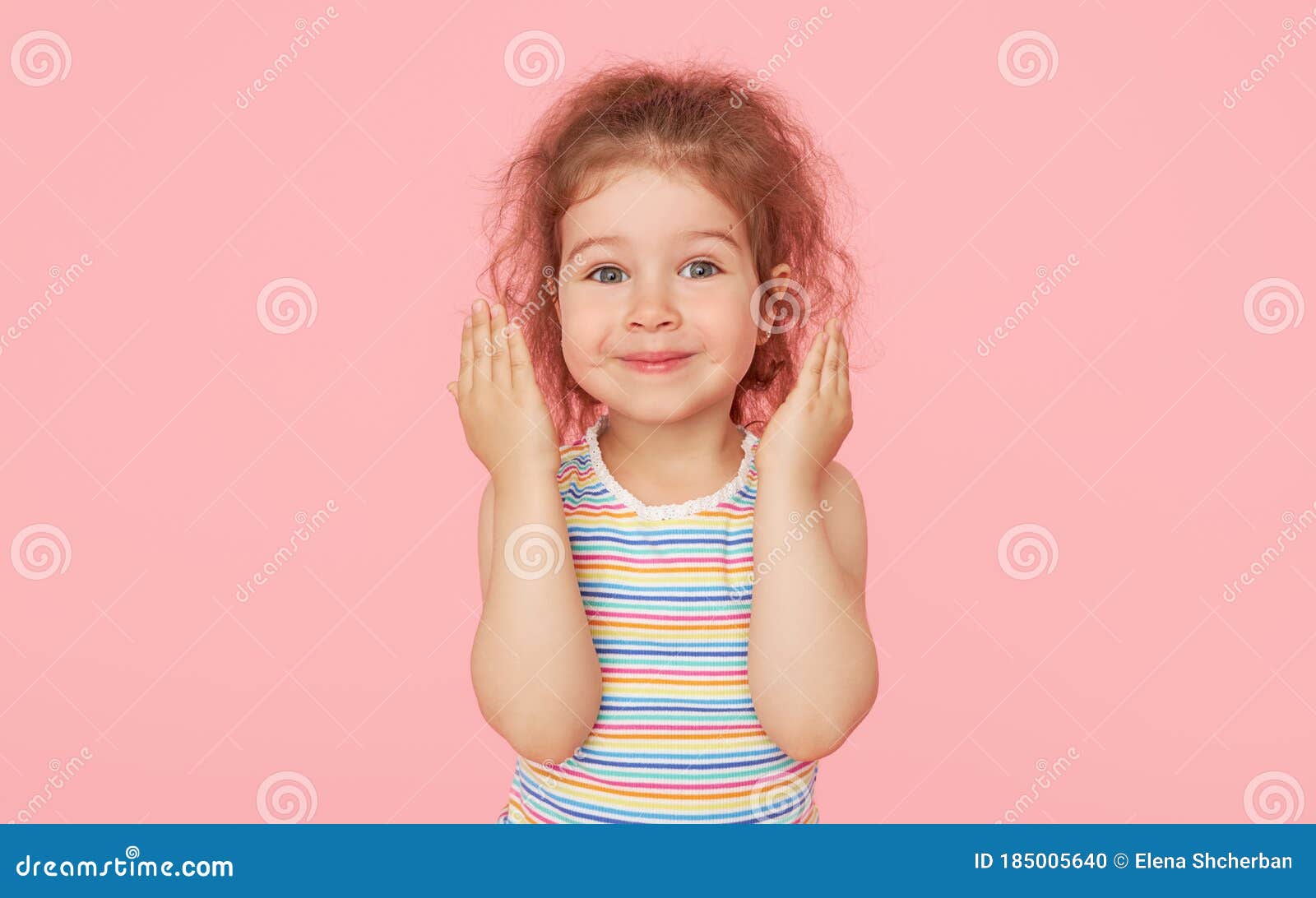 Linda adorable niña preescolar, de 3 a 4 años de edad, mira pensativamente  hacia arriba, sosteniendo su dedo en su sien, posando sobre un fondo rosa  con espacio de copia. retrato de
