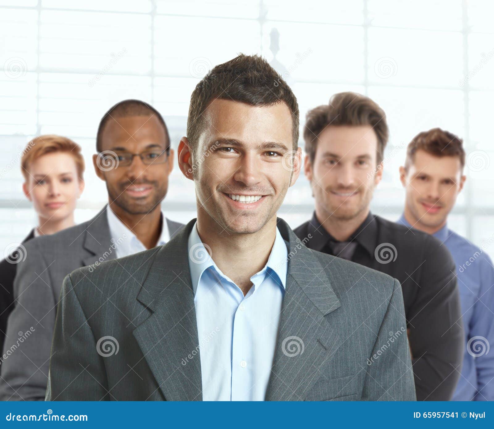 Retrato del hombre de negocios y del equipo felices. Retrato del hombre de negocios joven feliz y del businessteam joven en la oficina