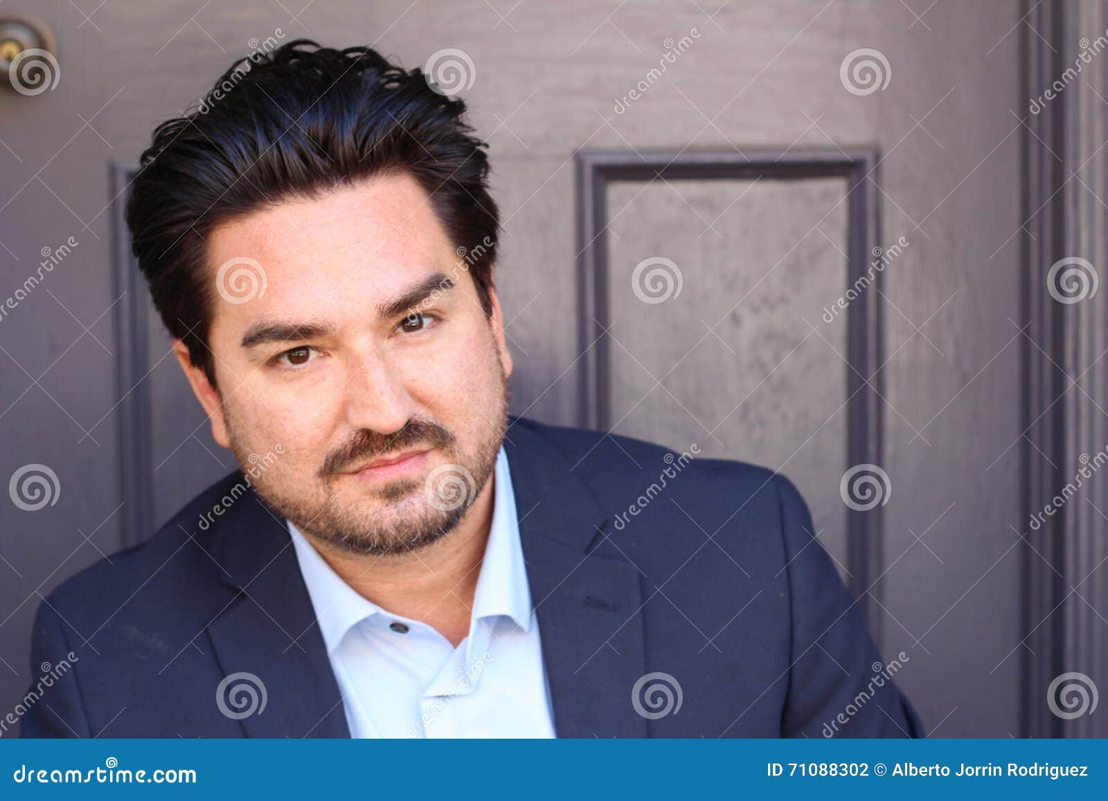 Retrato do close up de um homem de negócios contra o fundo da parede de tijolo