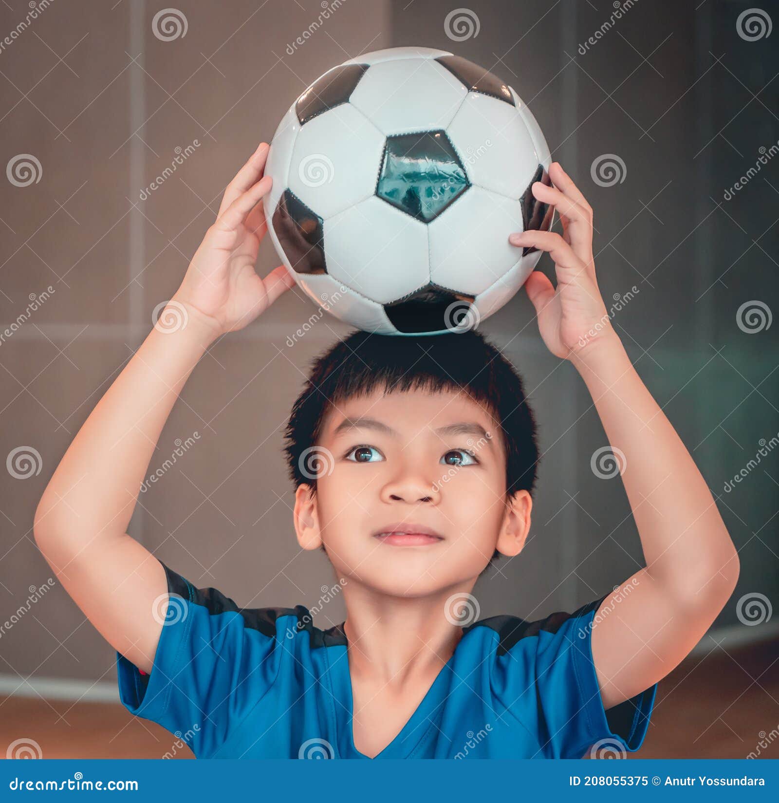 Um garoto segurando a velha bola de futebol antes de começar um jogo de  futebol