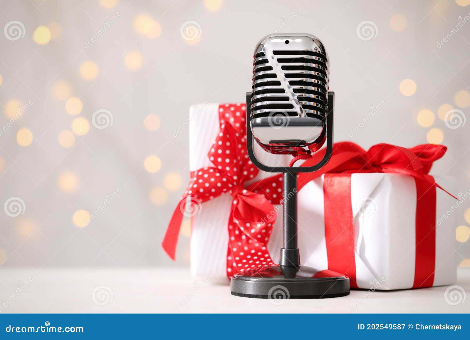 Retro Microphone and Gift Boxes on Table Against Blurred Lights, Space for Text. Christmas Music