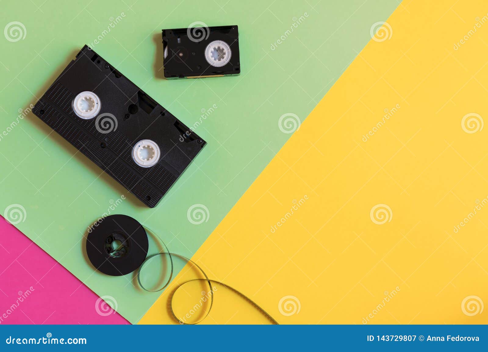 retro videocassette and film on a three-color pastel paper background. flat lay, minimal concept