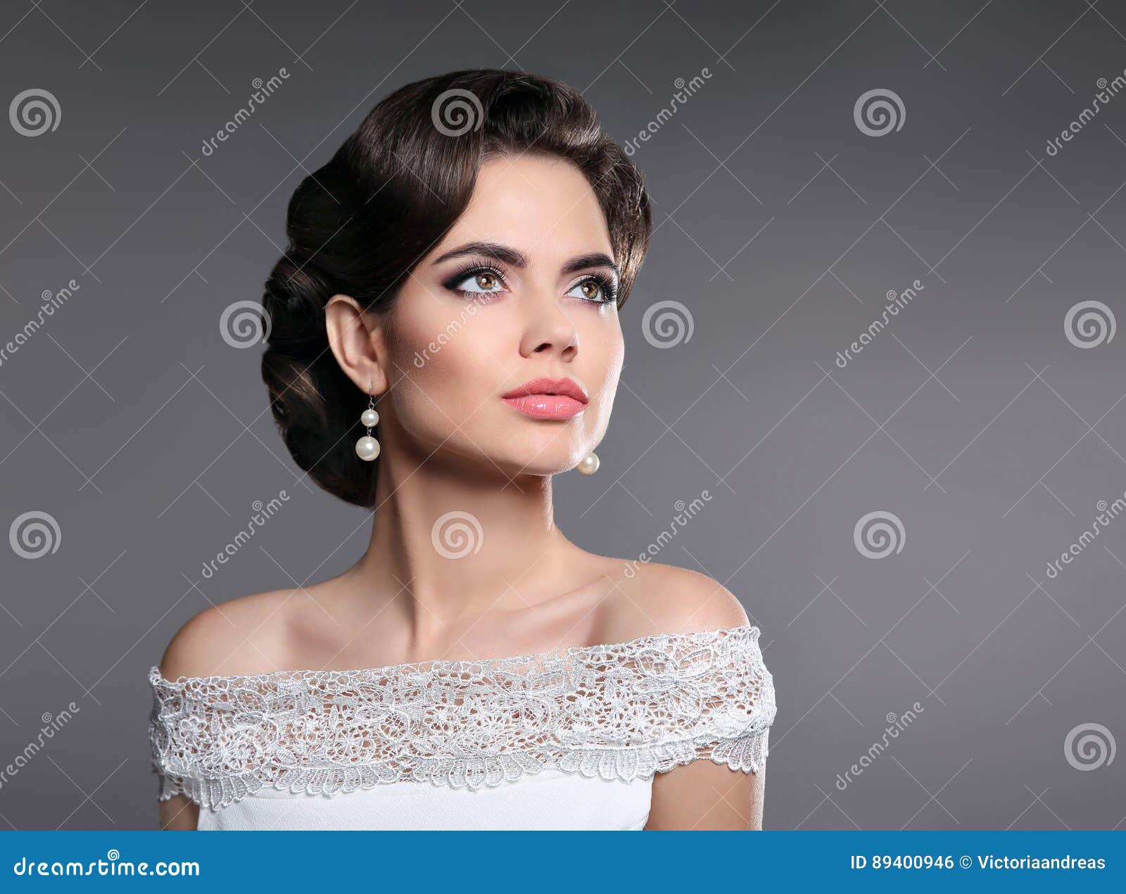 retro woman portrait. elegant lady with hairstyle, pearls jewelry set posing  on studio gray background.