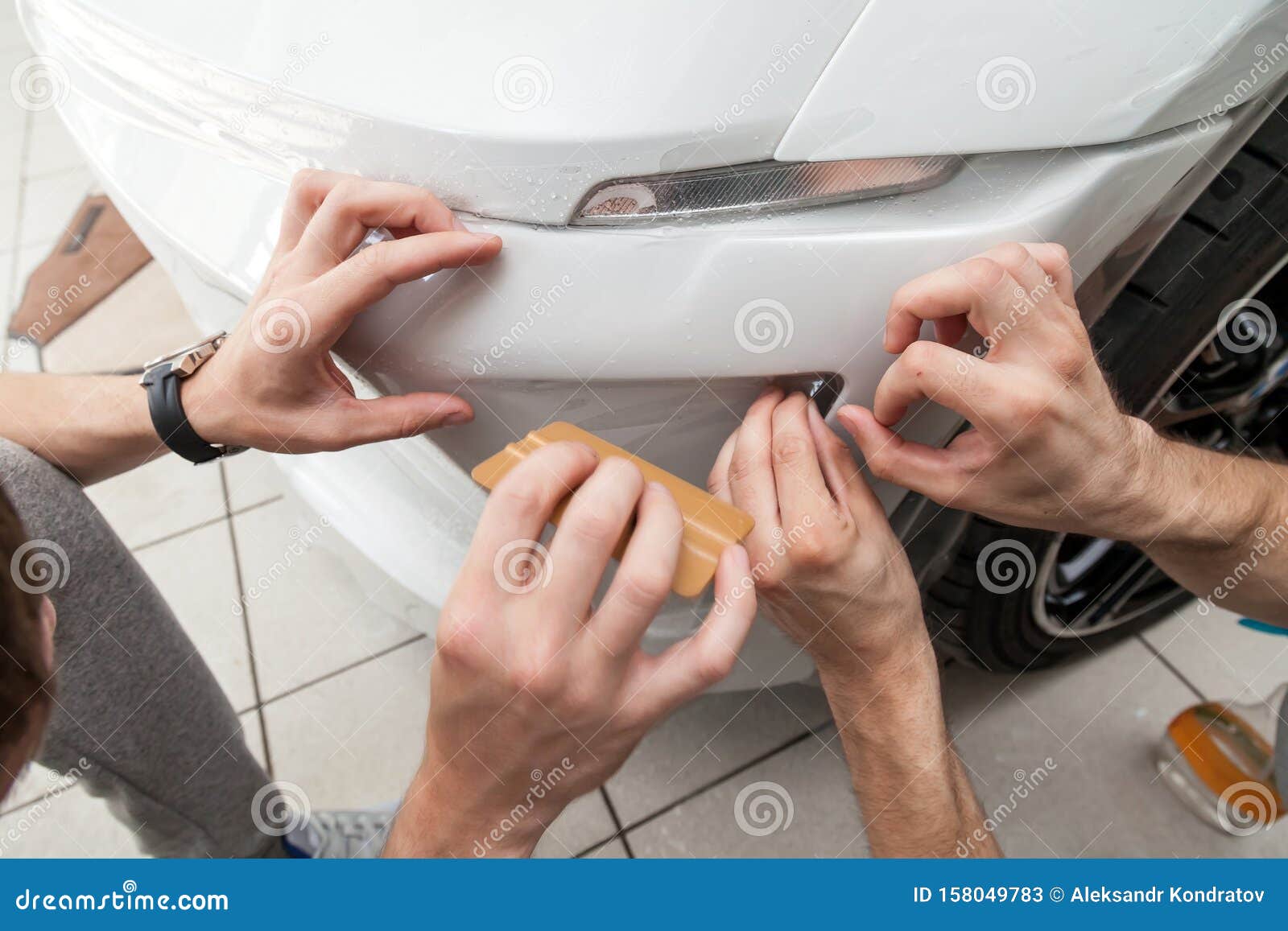 retrofitting the car with a solid transparent protective film, the master smooths the surface by squeezing air bubbles with a