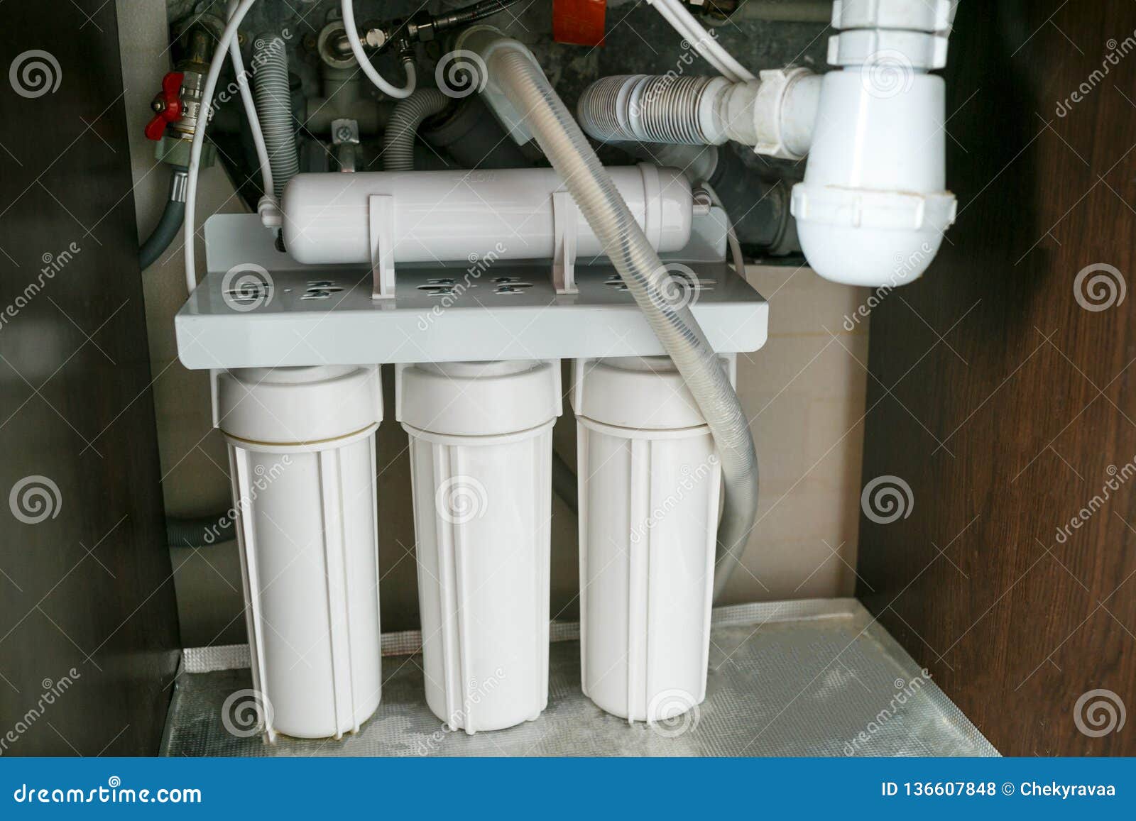 reverse osmosis water purification system at home. installation of water purification filters under kitchen sink in cupboard.