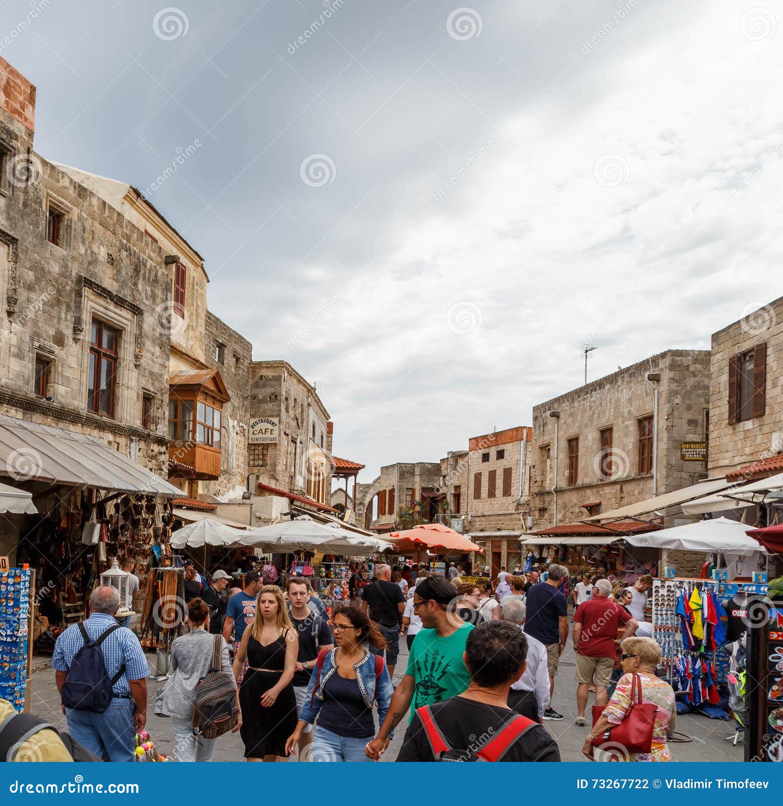 RHODOS, GREECE- JUNE 14 2016: Many tourists visiting and shopping at market street in old town Rhodos, Greece. RHODOS ISLAND, GREECE- JUNE 13: Many tourists visiting and shopping at market street in old town Rhodos, Greece on June 13, 2015. Shopping street leads to famous landmark of Suleymaniye Mosque.