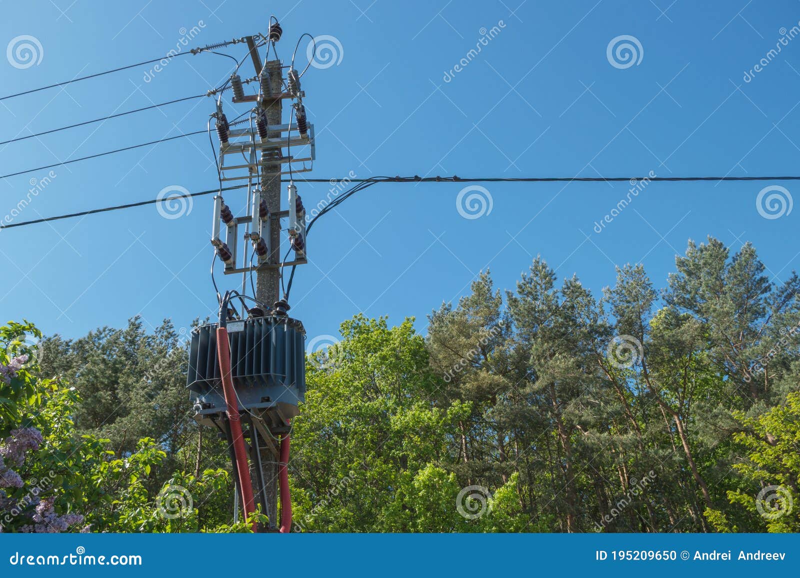 grey distribution transformer connected to incoming power cables from above and output cables from below in red corrugated tube