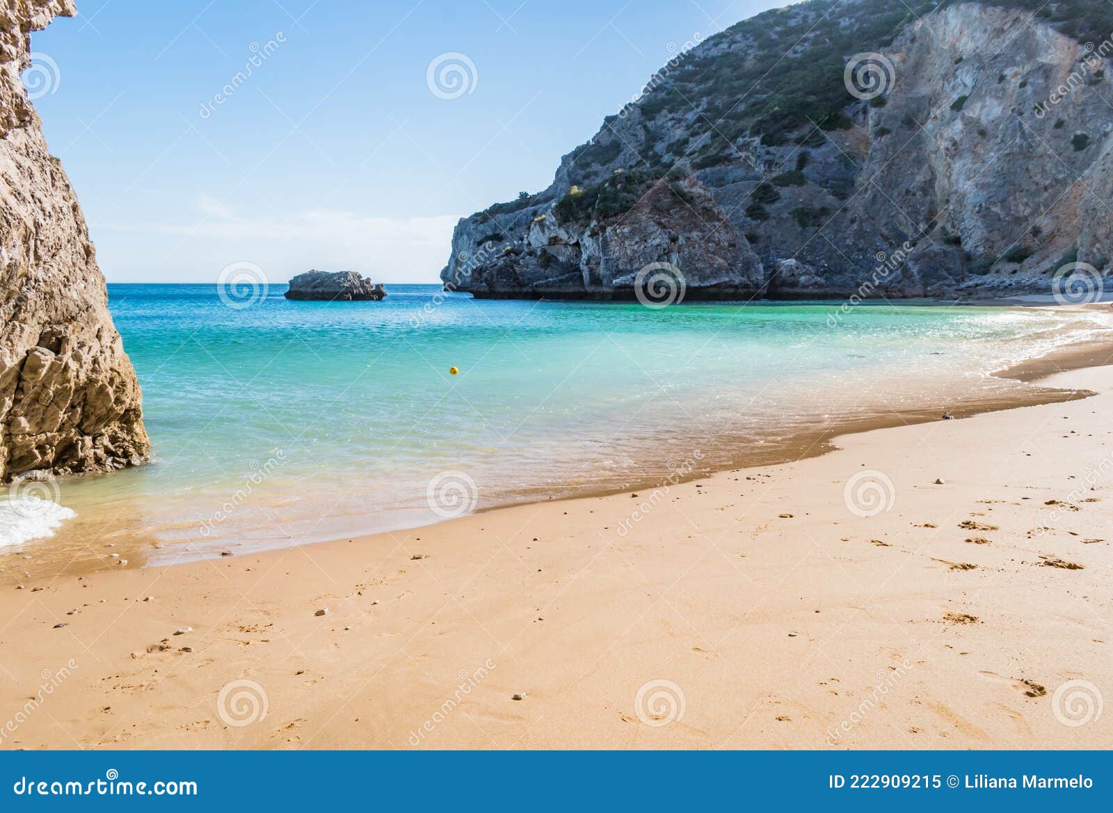 ribeiro do cavalo beach with clear turquoise water with rocks and a ball floating in the water, sesimbra portugal