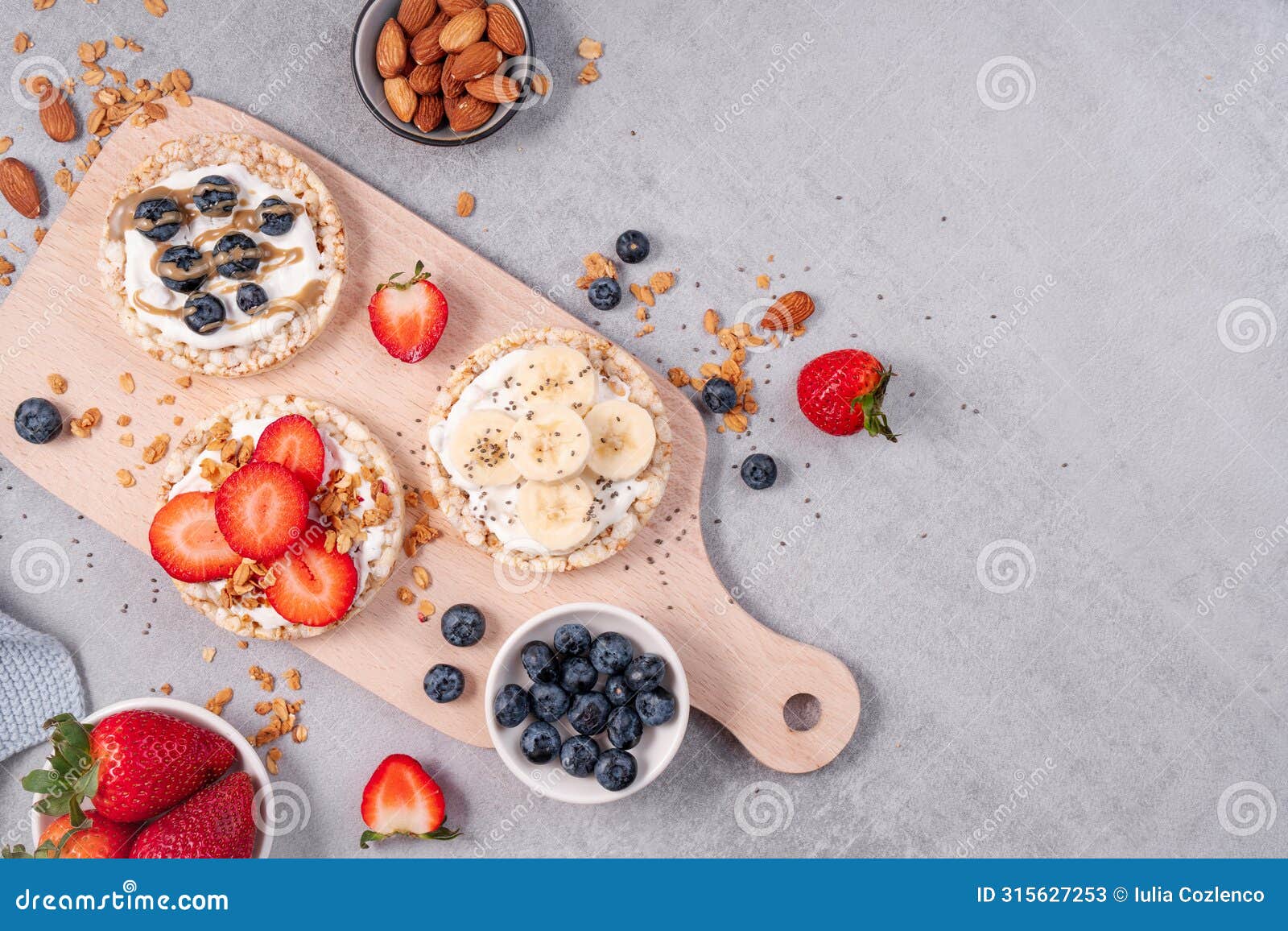 rice crackers healthy snack, crackers topped with banana, fresh berries, yogurt and granola, breakfast idea