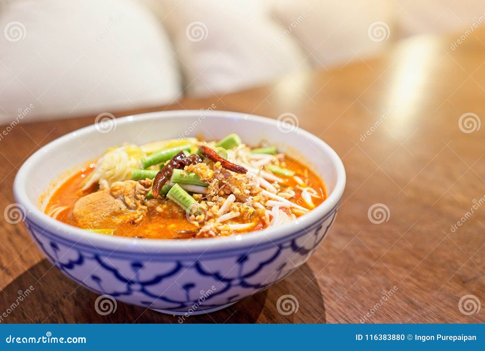 rice noodles with spicy pork sauce in bowl on wooden table. the local food of northern`s thailand, call `khanom jeen nam ngeaw