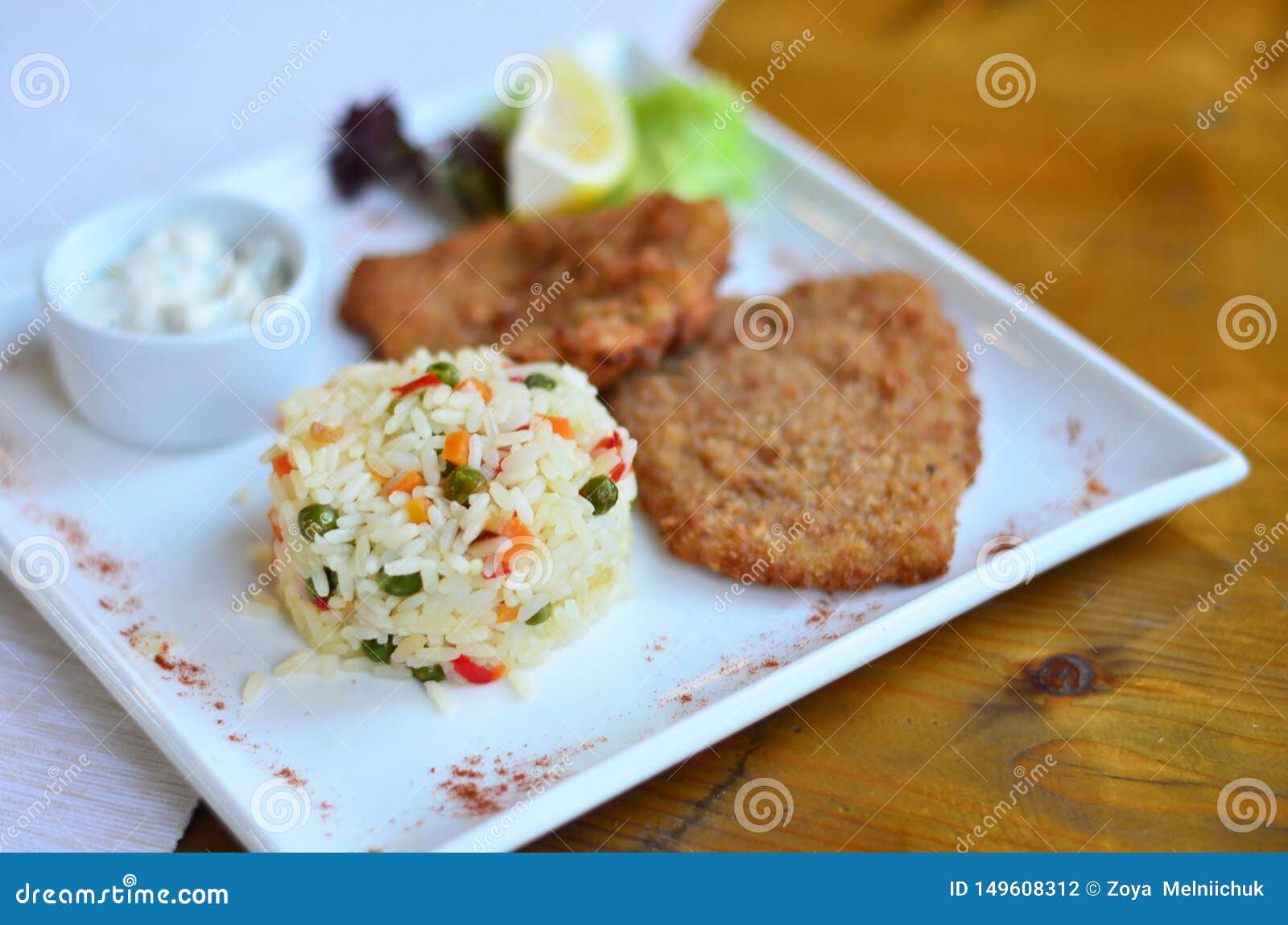 Rice with vegetables with a piece of fish. Risotto with vegetables and grilled fish on a plate