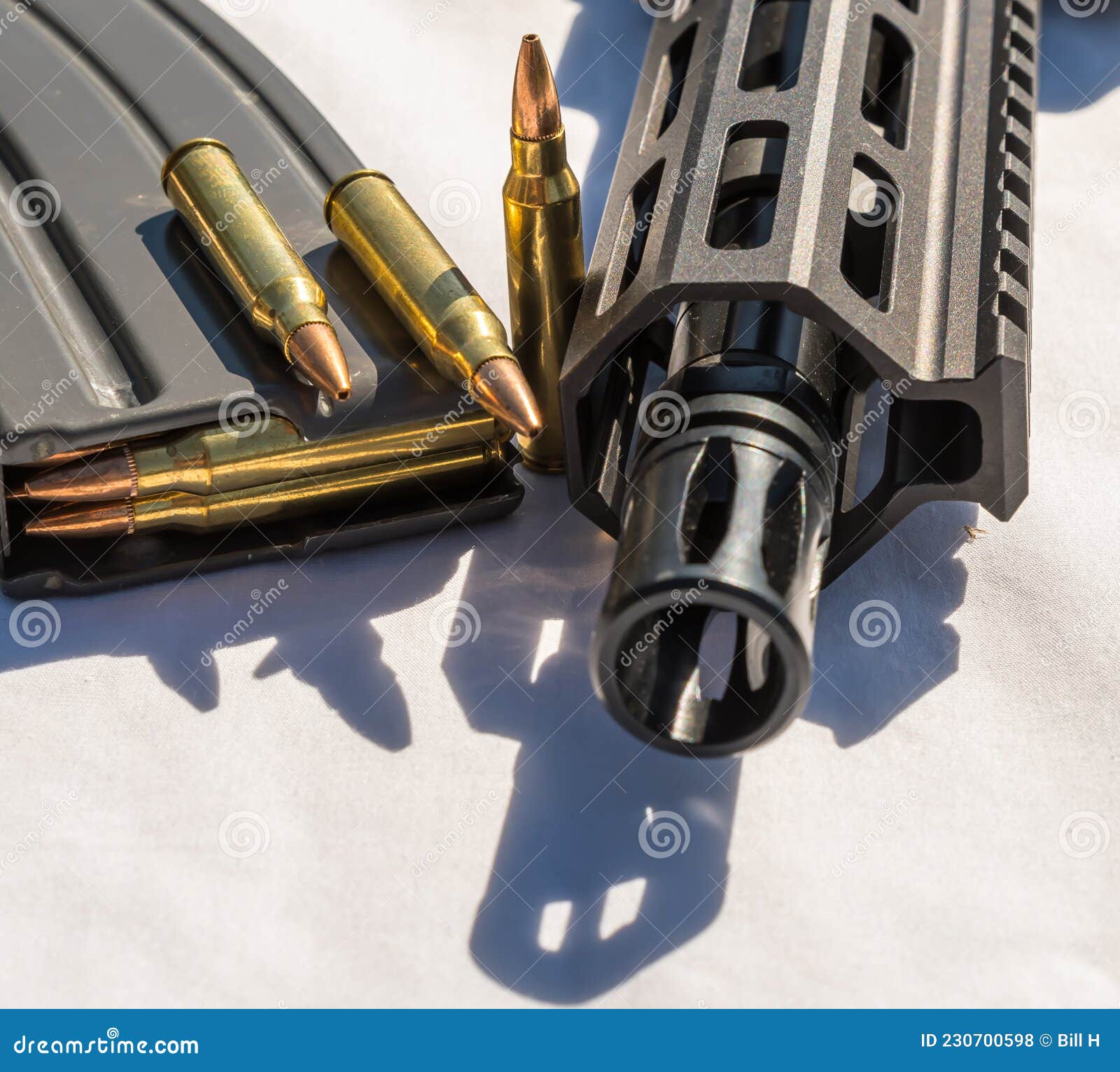 a rifle magazine loaded with 223 caliber ammunition with three extra bullets next to and on top of it with the barrel and muzzle o