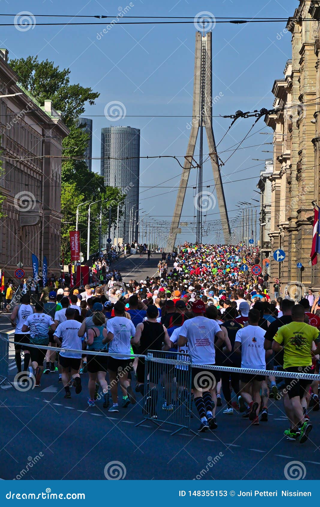 Riga Lettland - Maj 19 2019: Maratonl?pare som ankommer till den Vansu bron. Maratonl?pare som ankommer till den Vansu bron som fyller den hela gatan med spektakul?r sikt