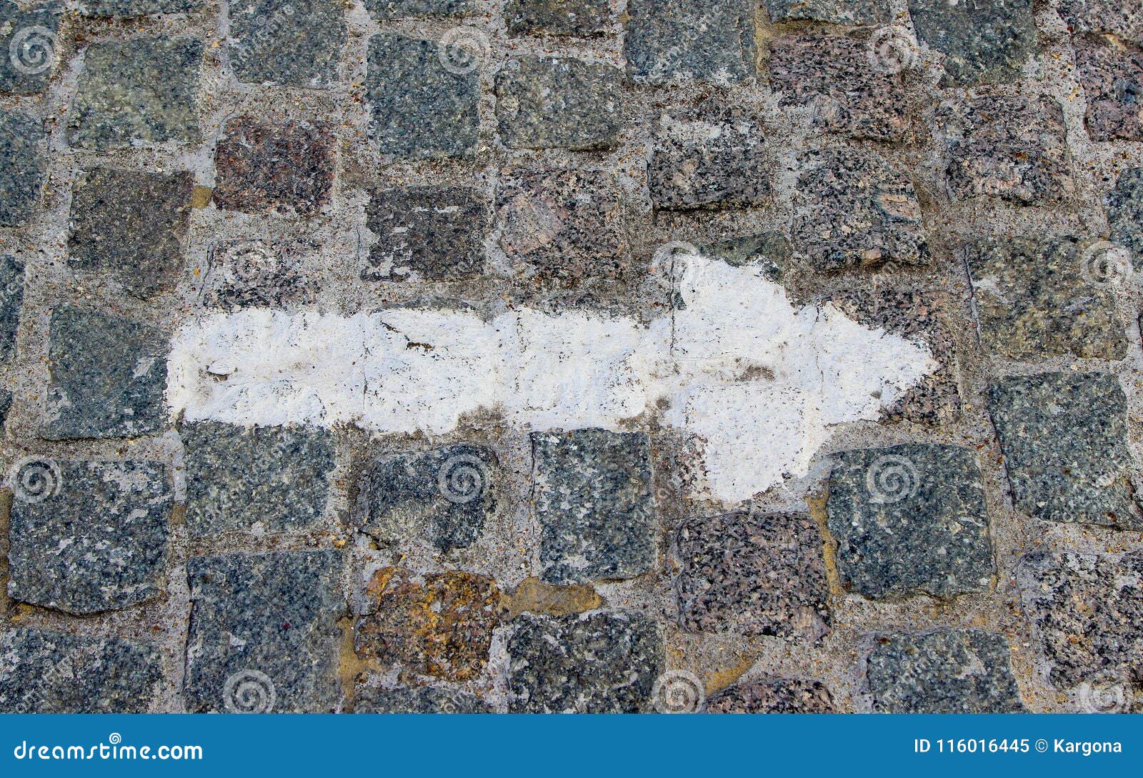 a rightwards arrow painted with white paint on the old stoneblock pavement cobbled with square granite blocks