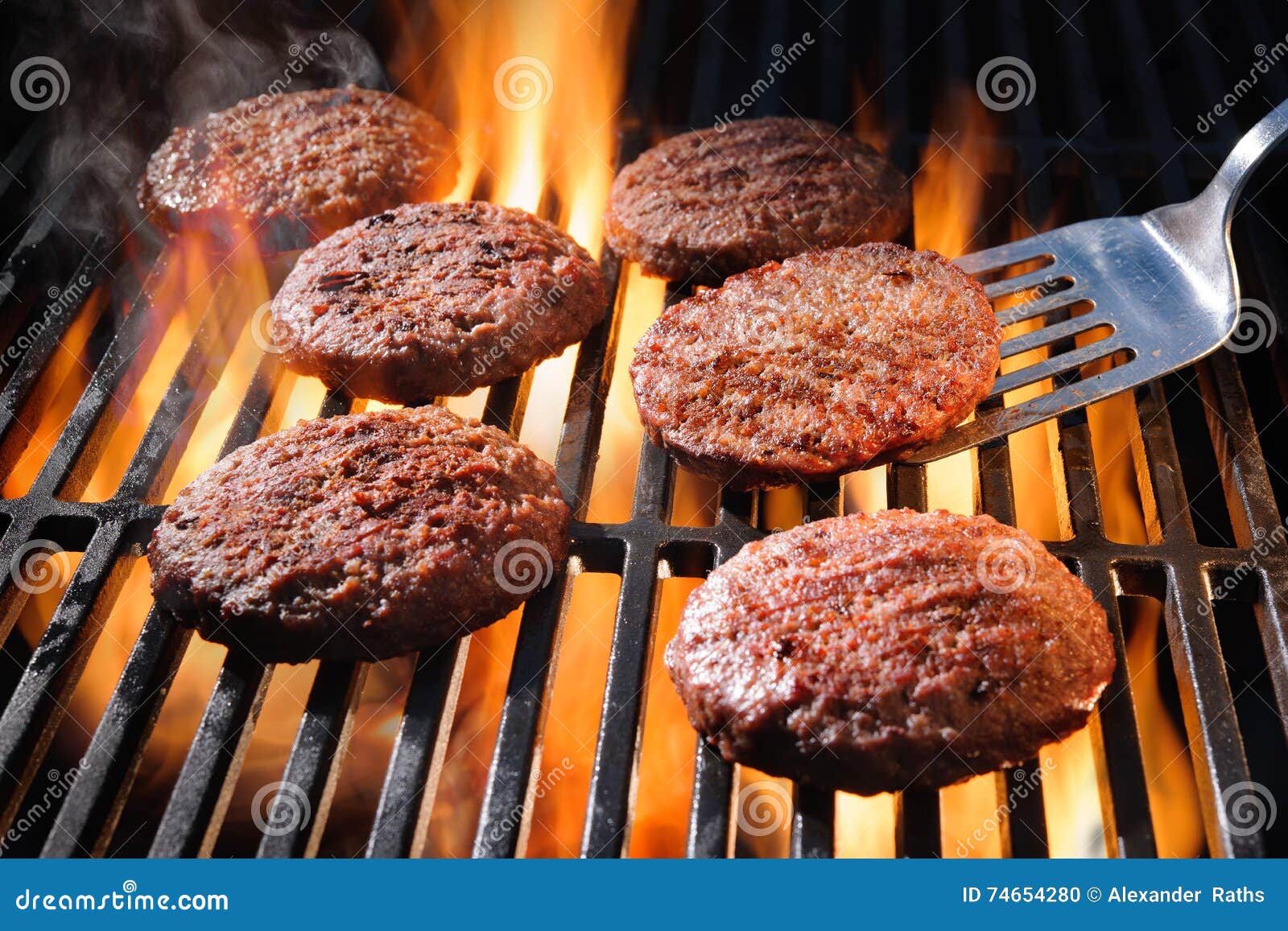 Rindfleischhamburgerpastetchen, die auf dem Grill zischen. Saftige Rindfleischhamburgerpastetchen, die über heißen Flammen auf dem Grill zischen