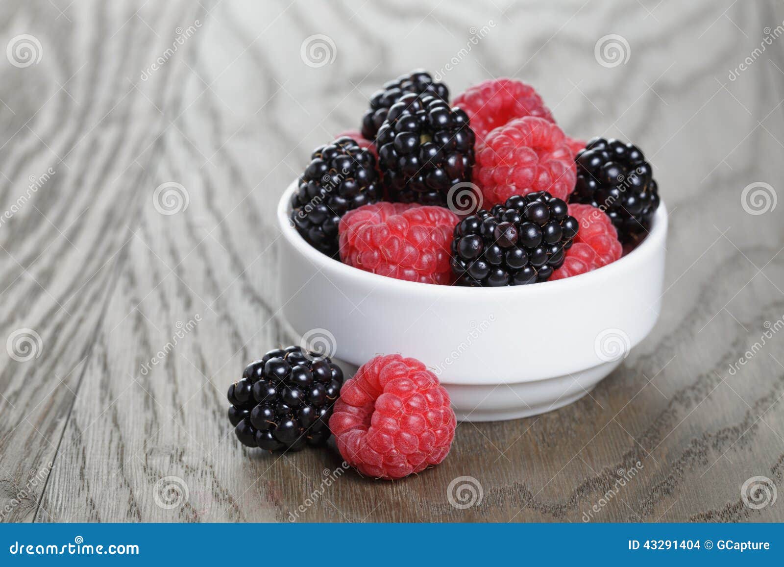Ripe Blackberries and Raspberries in White Bowl on Old Oak Table Stock
