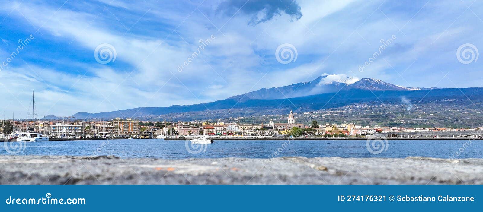 porto di riposto e l'etna sullo sfondo vista dal mare durante giornata estiva con barche e chiesa del porto