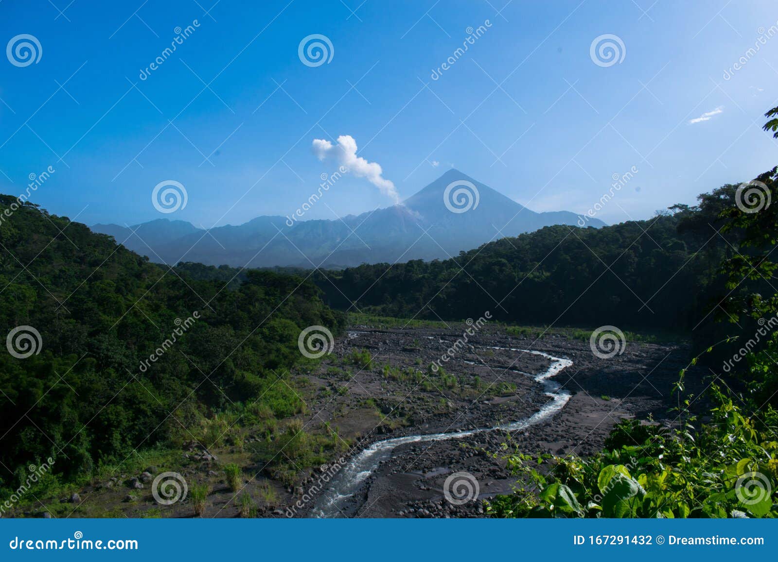river in the middle of the jungle with two volcanoes in the background