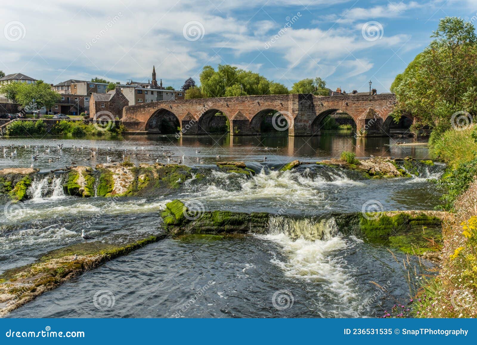 the river nith flowing over the caul weir in dumfries, during summer in scotland