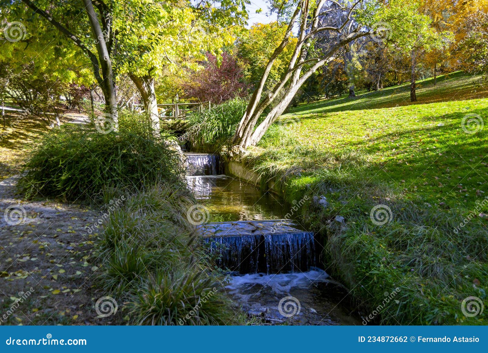 river-stream passing through parque del oeste, madrid park with some autumn colors on a clear day in madrid, spain.