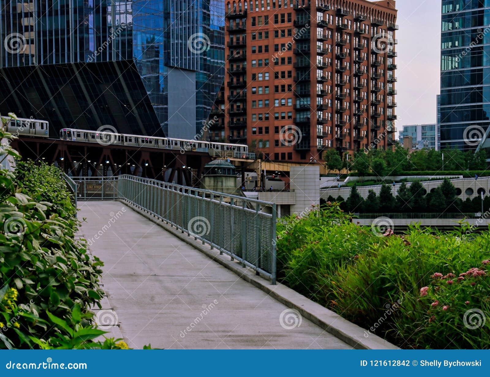 river walk ramp leading up to wacker drive with elevated `el` trains crossing over chicago river.