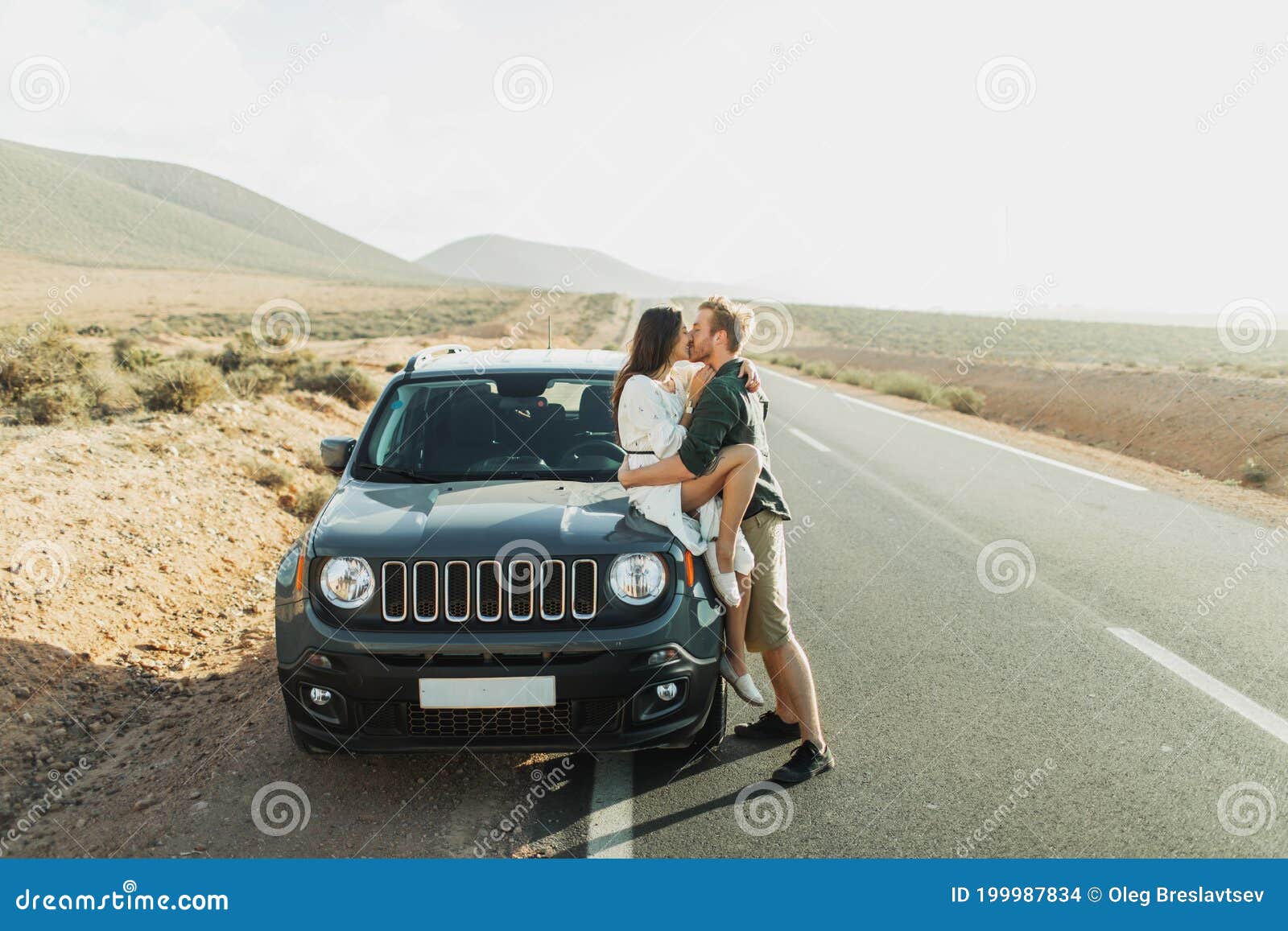Road Trip Concept. Young Hipster Couple Kissing in Car on Highway