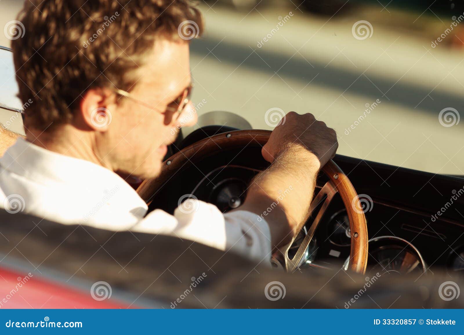 Road trip. Handsome man driving a convertible car, focus on hand