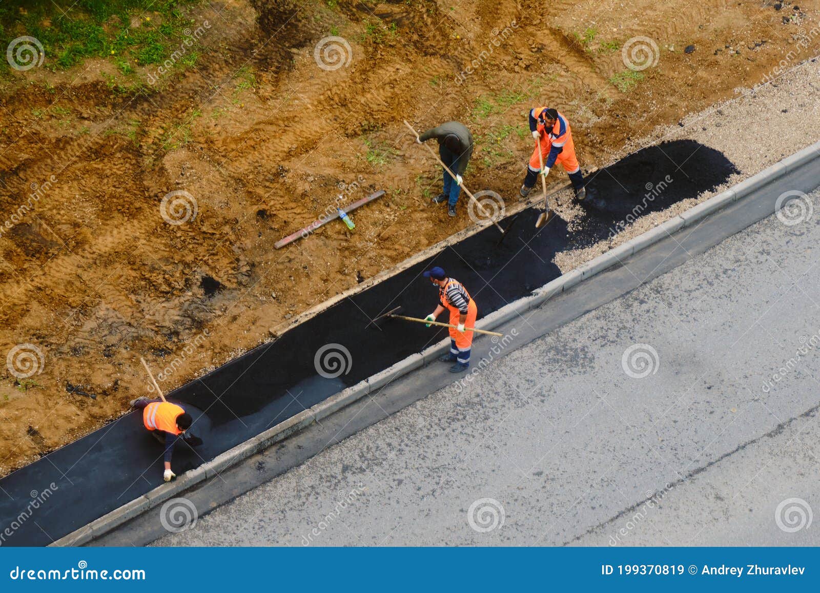 Road Workers Lay Asphalt Shovels on the Sidewalk Near the Road Stock