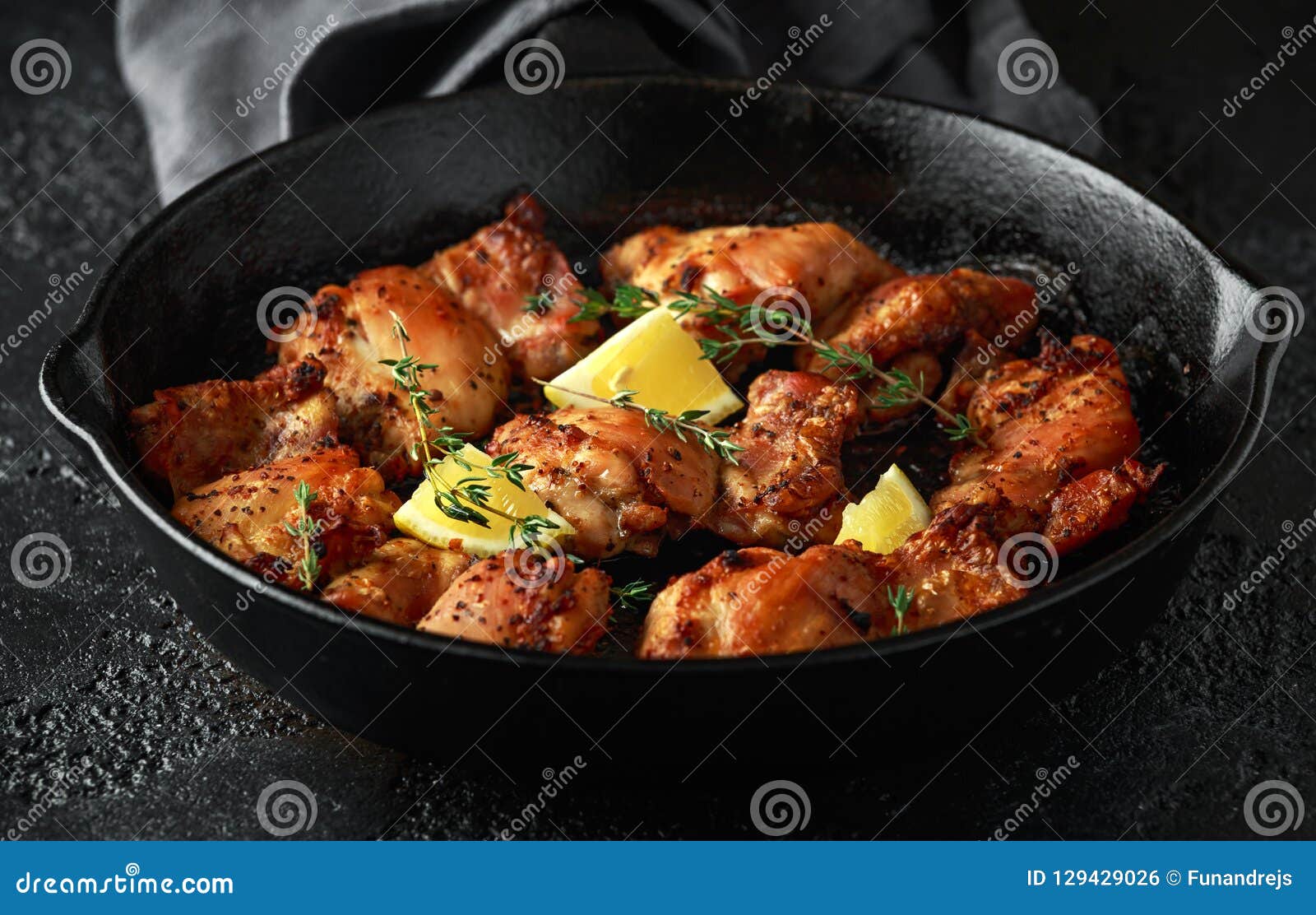 roasted boneless skinless chicken thighs in lemon and thyme dressing served in vintage cast iron skillet, frying pan