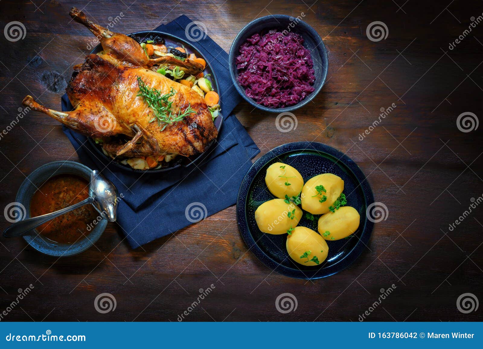 roasted duck with potatoes, red cabbage and sauce, a festive meal on a dark rustic wooden table, copy space, high angle view from