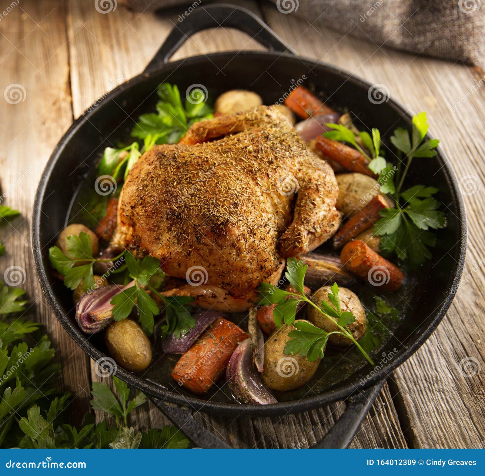 roasted whole chicken with vegetables in a cast iron pan