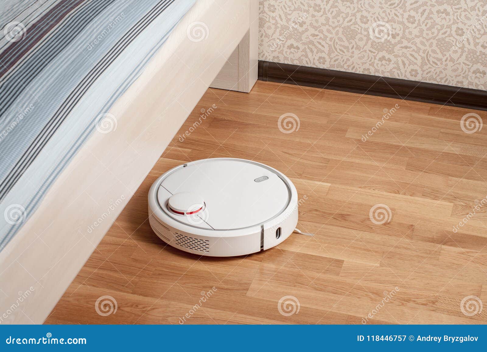 Robot Vacuum Cleaner Runs On Wood Parquet Floor Under Bed In