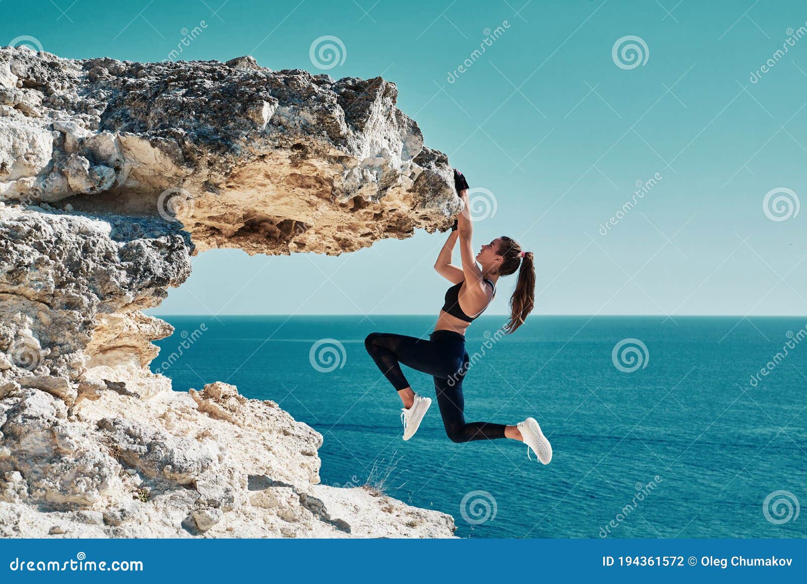 rock climbing. sport. active lifestyle. athlete woman hangs on sharp cliff. seascape. outdoors workout. high resilience