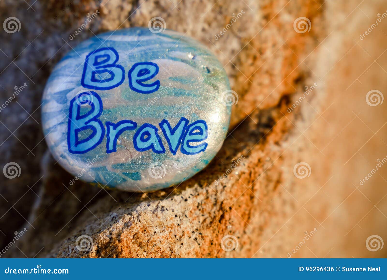 a rock painted silver and light blue stating be brave