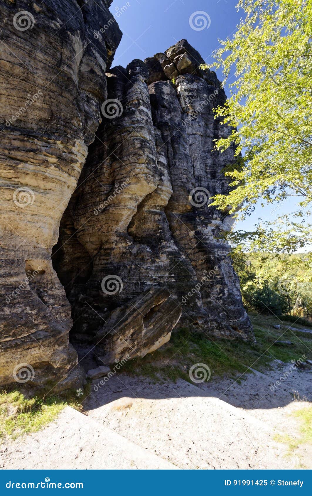 Rock täckas fullständigt med skugga. Skugga av träd täcker fullständigt vagga i det ljusa solljuset