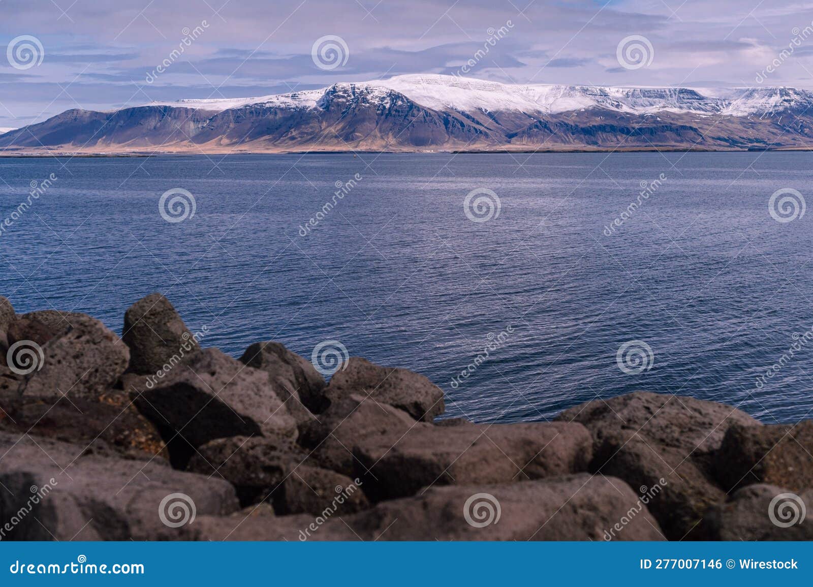 rocks near the ocean with mountain in the background
