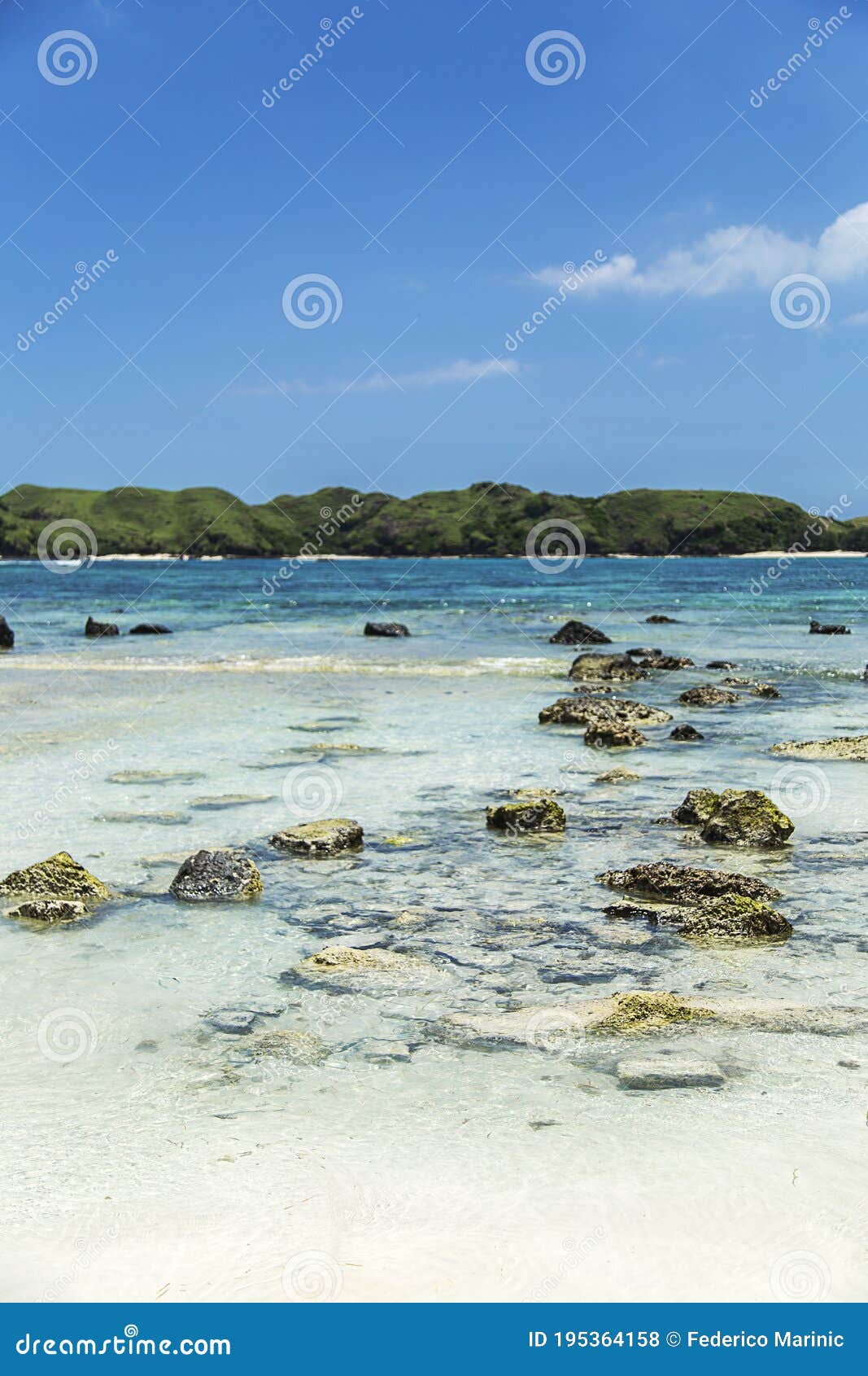rocks in a transparente light blue sea and mountains at the background