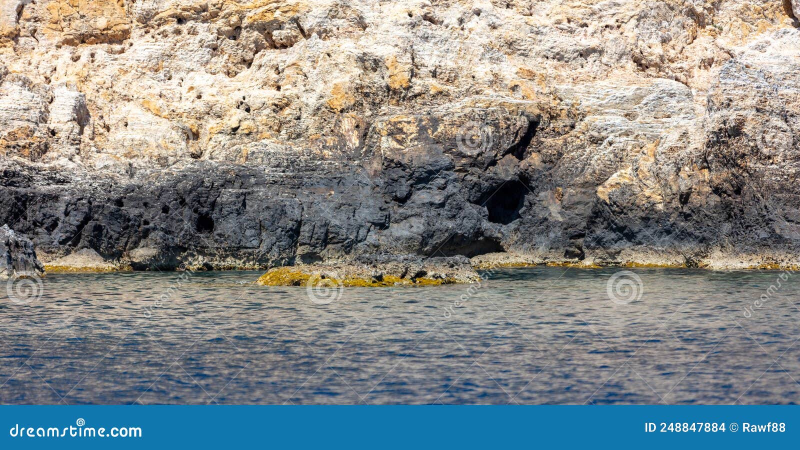 rocky coast, cliffs and caves, rippled aegean sea. cyclades greece. seascape near nios island