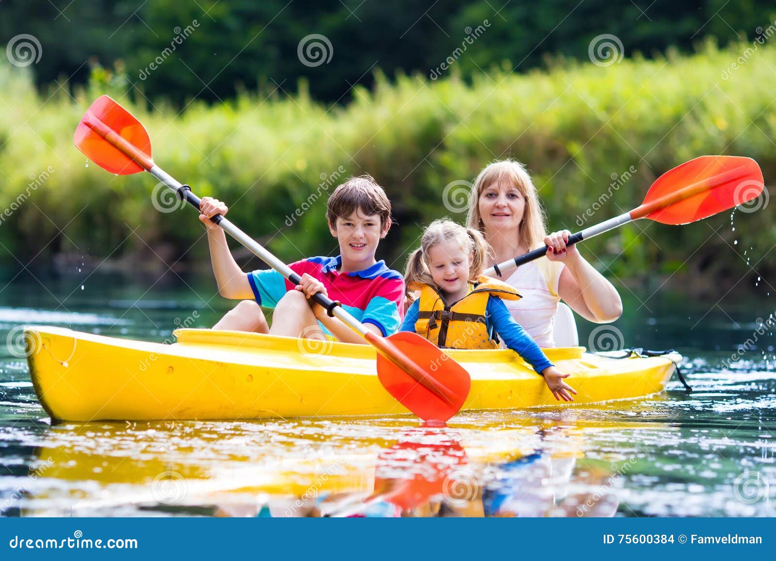 Rodzinna cieszy się kajak przejażdżka na rzece. Szczęśliwa rodzina z dwa dzieciakami cieszy się kajaka jedzie na pięknej rzece Matka z małej dziewczynki i nastolatka chłopiec kayaking na gorącym letnim dniu Wodnego sporta zabawa Czółno i łódź dla dzieci