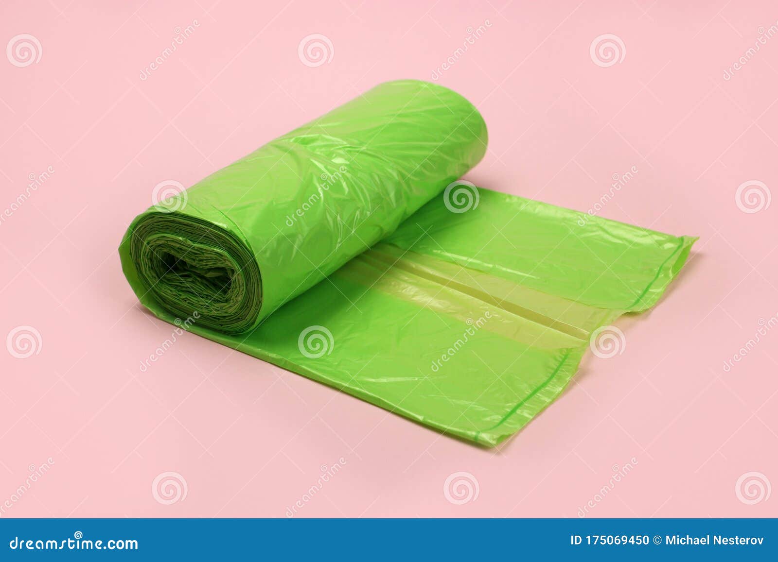 Roll of Plastic Green Garbage Bags on Pink Background Stock Photo
