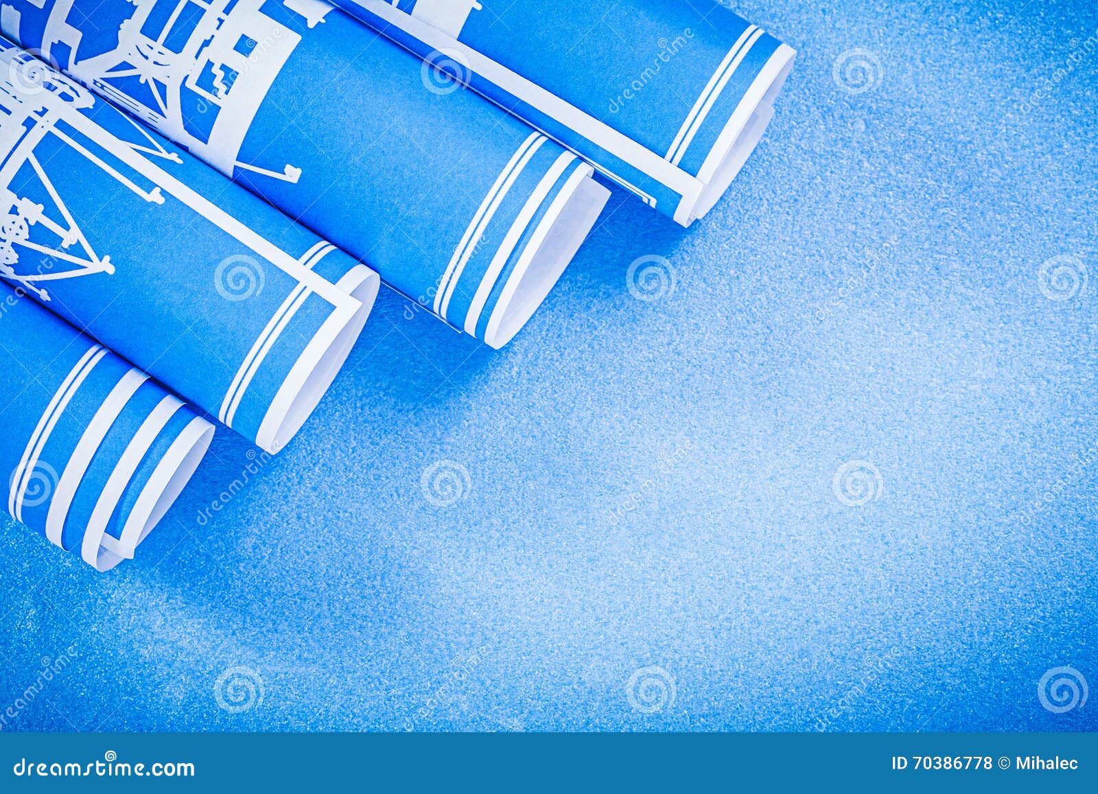 Rolled Construction Drawings on Blue Background Directly Above Stock