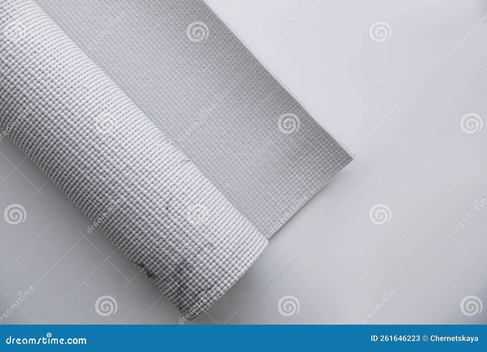 rolled karemat or fitness mat on tiled floor, top view