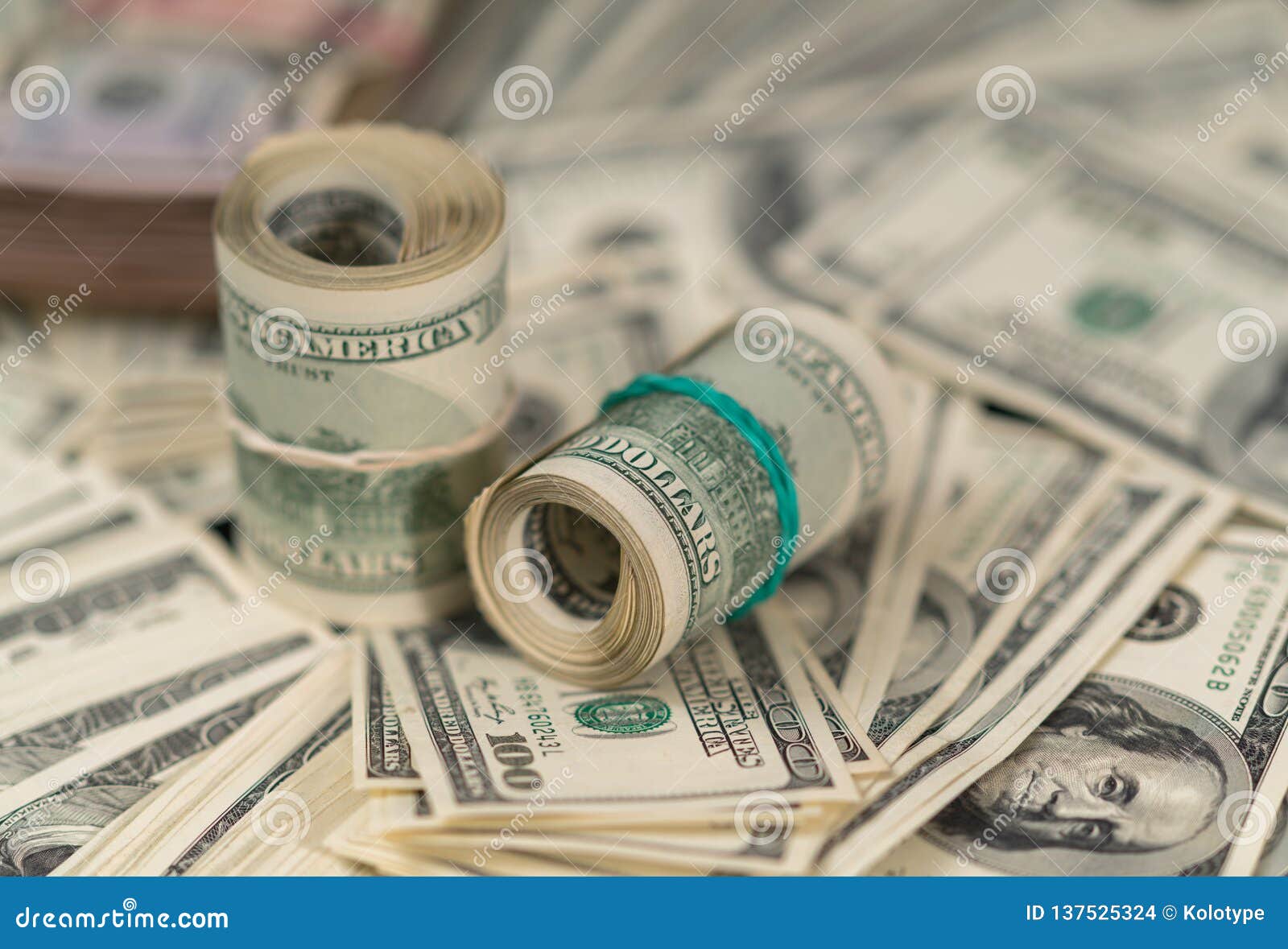 rolls of 100 dollar bills on piles of money