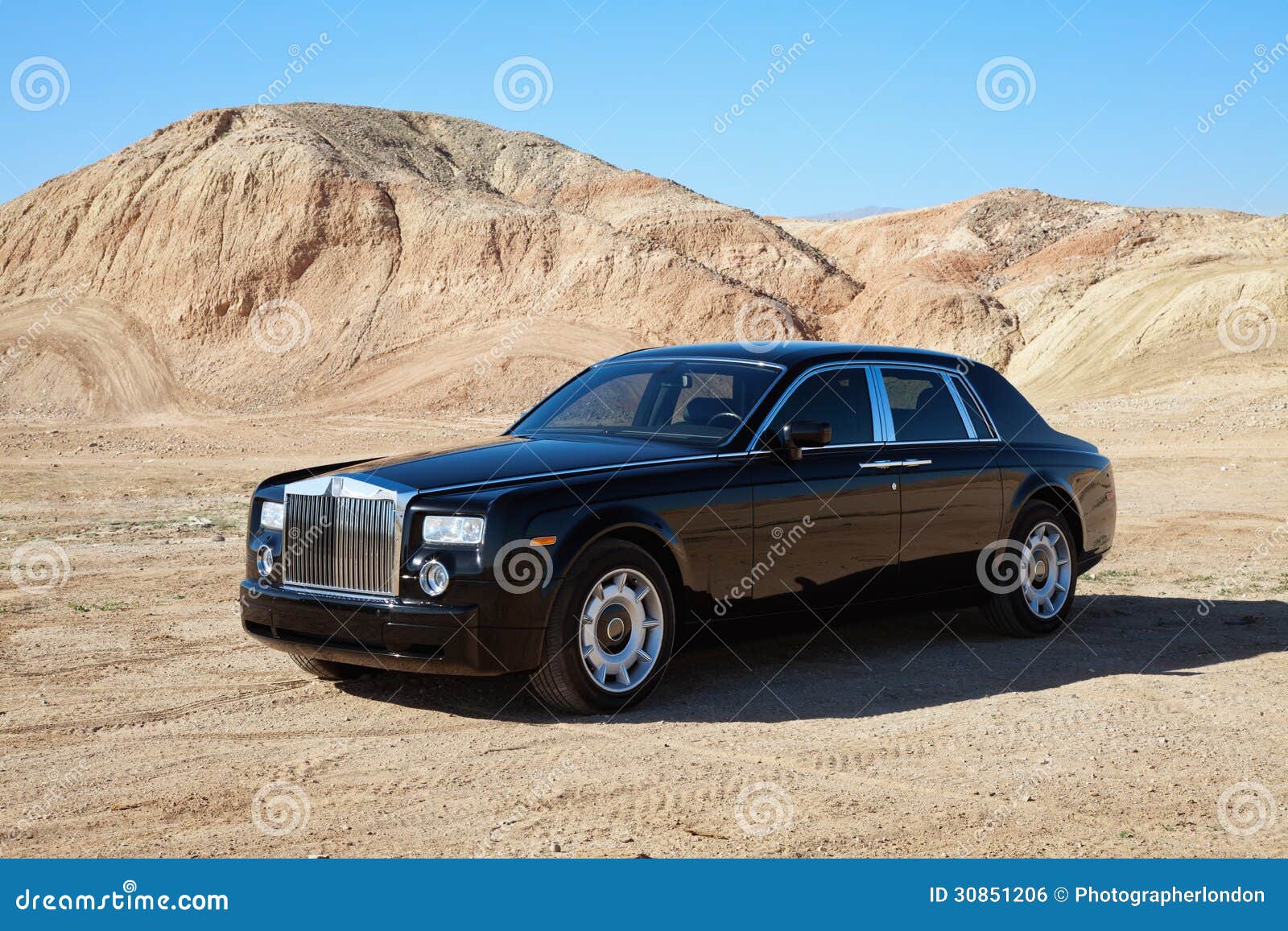 rolls royce car parked on unpaved road in front of mountains