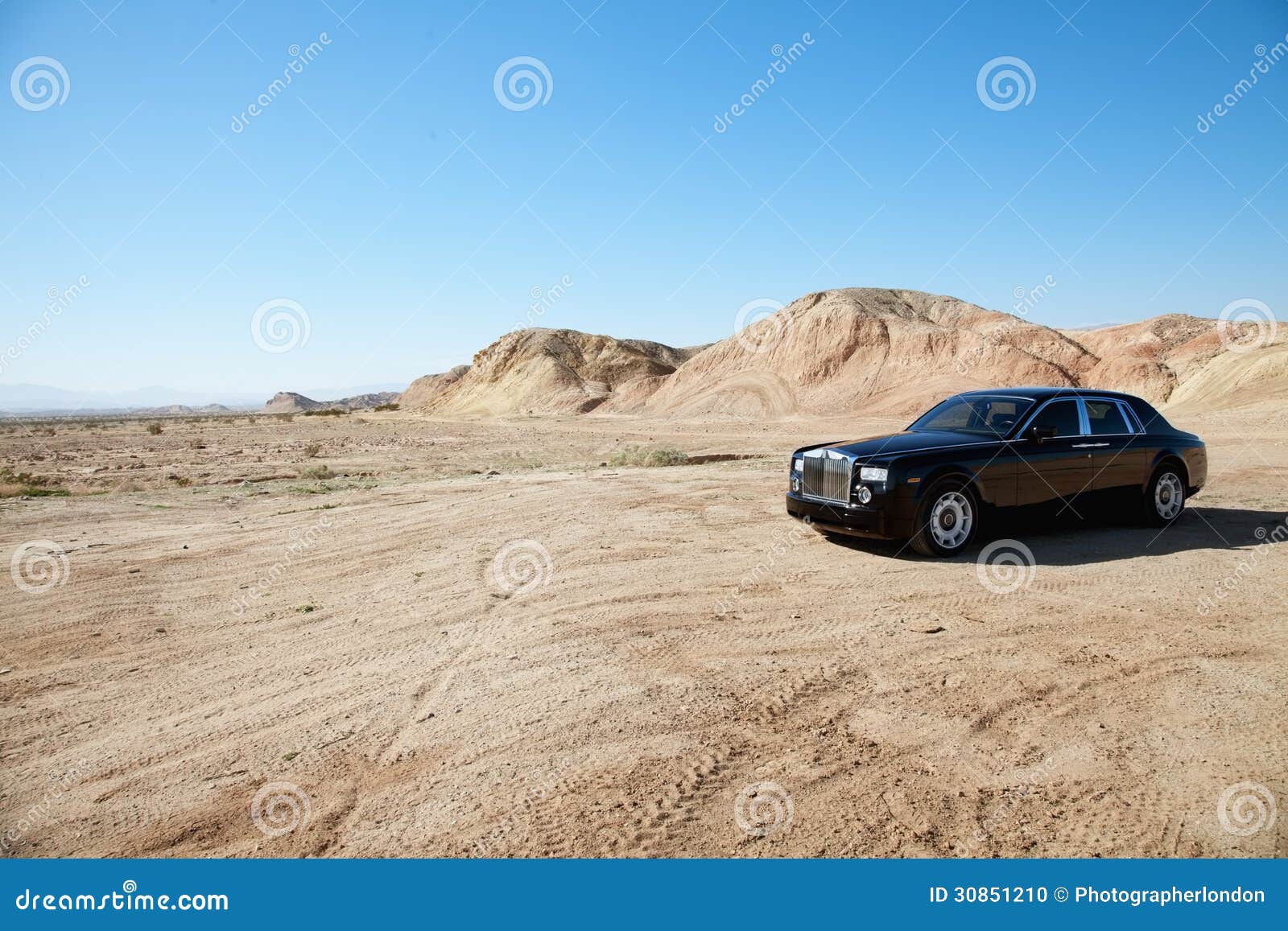 rolls royce car parked on unpaved road in front of mountains