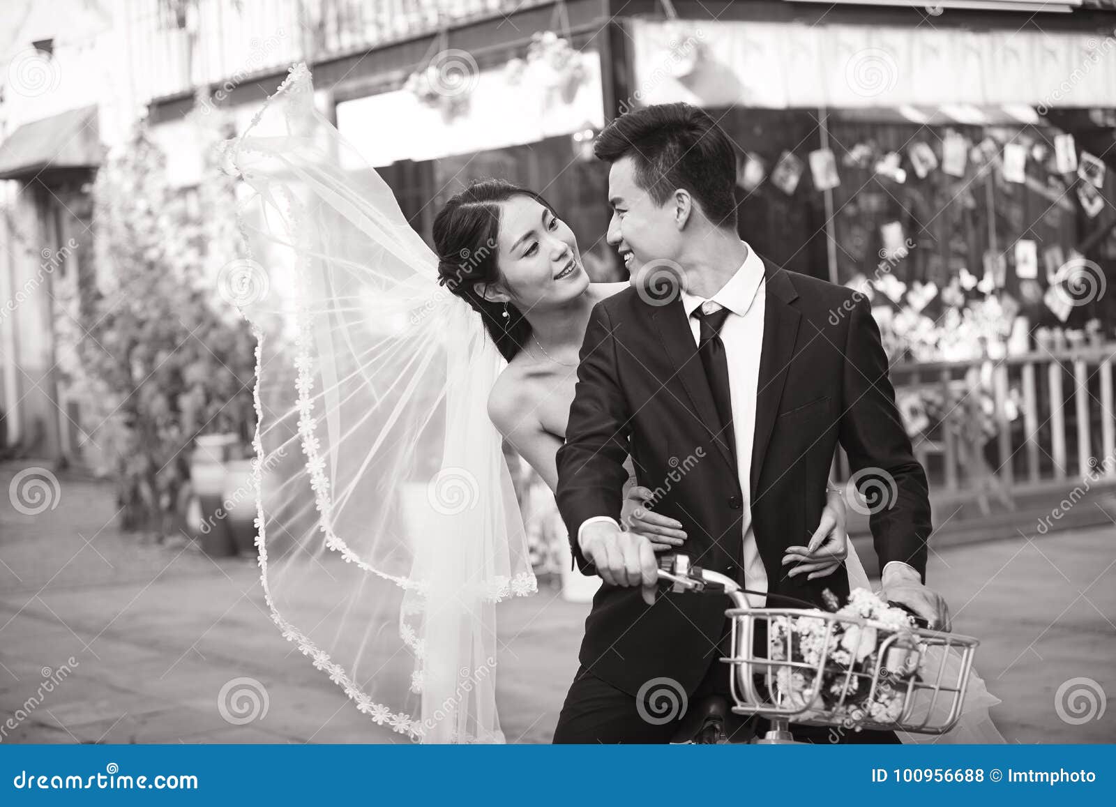 romantic asian newly-wed riding a bicycle