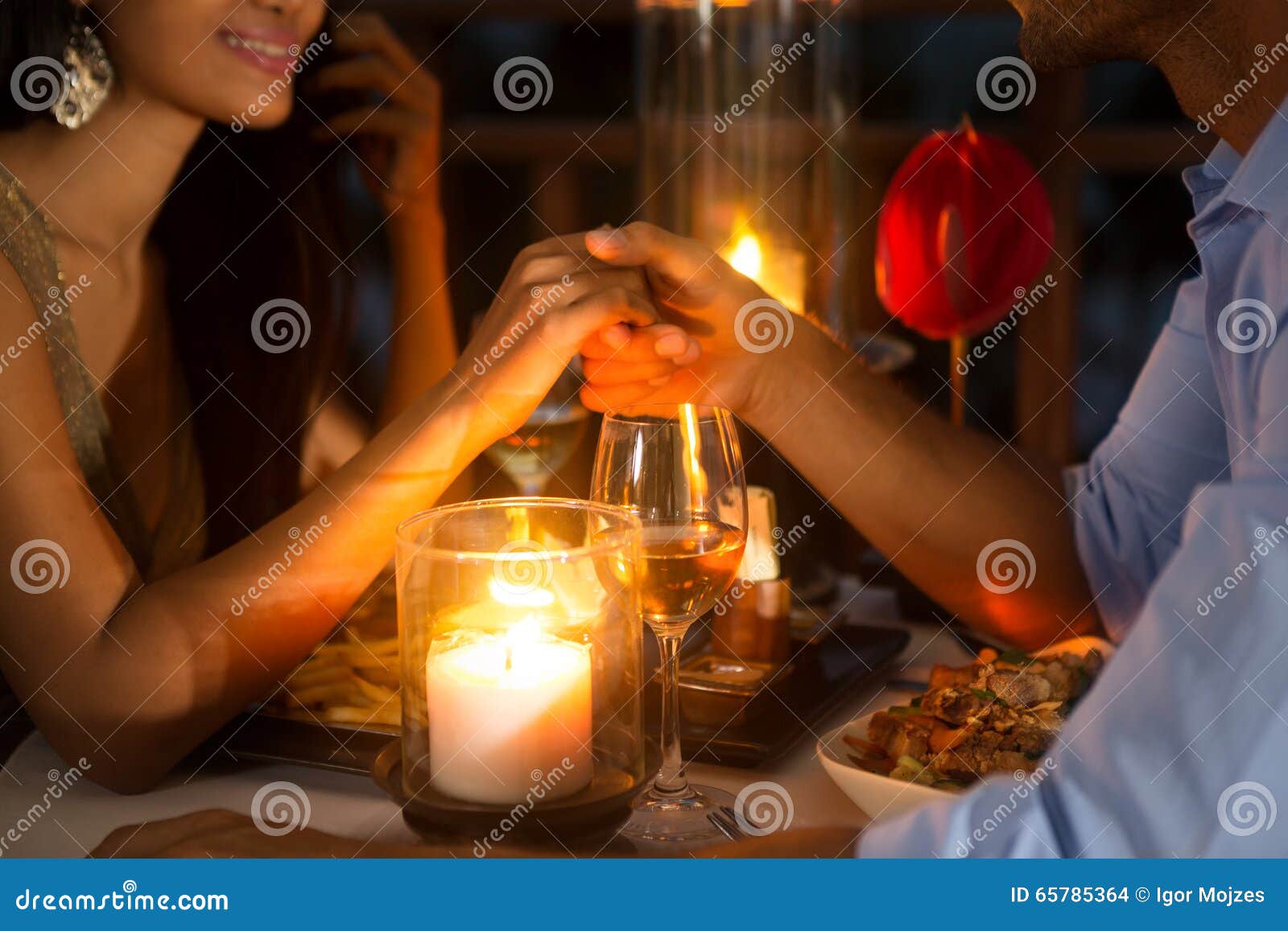 romantic couple holding hands together over candlelight