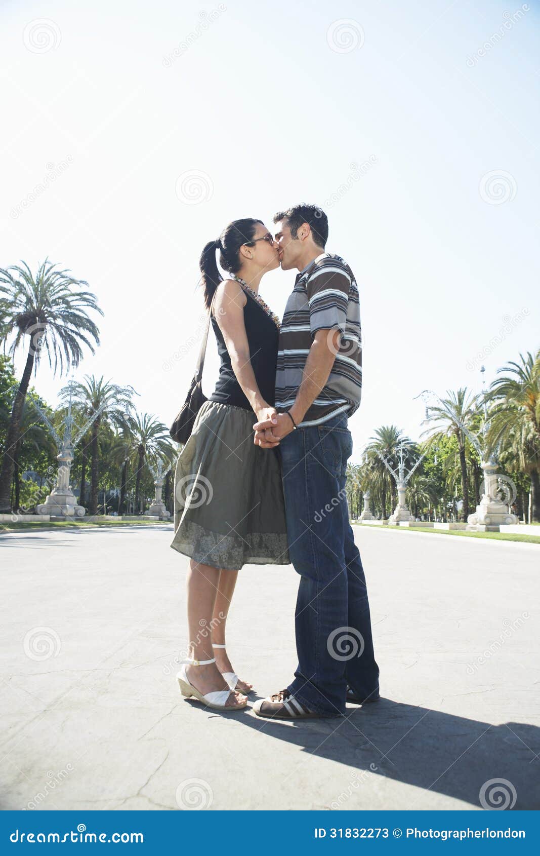 Romantic Couple Kissing On Road. Side view of romantic young couple kissing on road